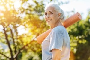 cheerful-senior-woman-going-to-enjoy-yoga-in-the-park