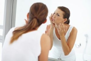 woman-examing-skin-in-mirror