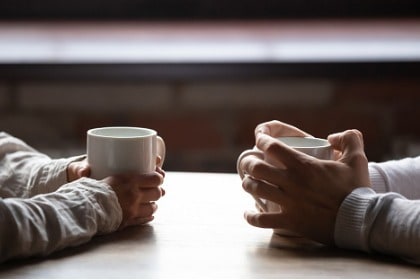 conversation-woman-and-man-holding-cups-of-coffee-on-table