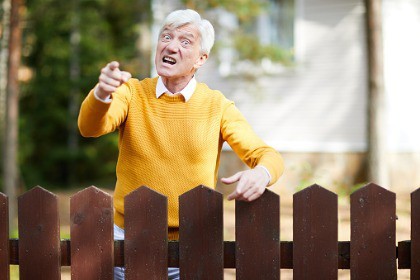 irritated_angry_unhappy_man_standing_behind_fence
