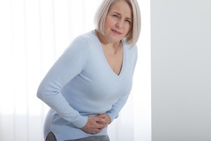 woman with flatuence gripping stomach