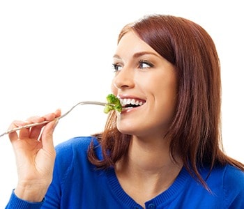 Woman Smiles Eating Broccoli