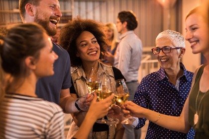 group of people at party clinking wine glasses